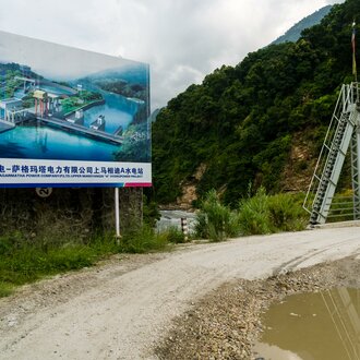 The future appearance of the chinese Upper Marsyangdi hydroelectric powerplant project is displayed on a big signboard | © Frank Bienewald / Alamy Stock Photo